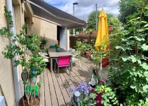 eine Holzterrasse mit einem Tisch und einem gelben Regenschirm in der Unterkunft Chambre salle de bain privée à 20 minutes de Paris in Fontenay-sous-Bois