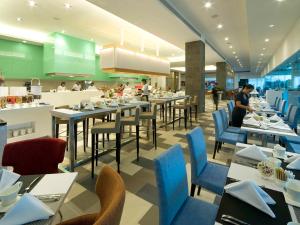 un restaurante con mesas y sillas y gente de fondo en Pullman Kuching, en Kuching