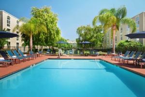 uma piscina com cadeiras e guarda-sóis em Hilton Oakland Airport em Oakland