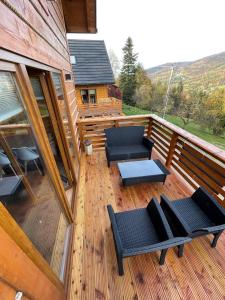 a wooden deck with chairs and tables on a cabin at Domki na Szlaku in Brenna