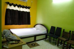 a small room with a bed and two chairs at Geetanjali in Bolpur