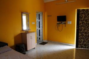 a bedroom with yellow walls and a room with a television at Geetanjali in Bolpur