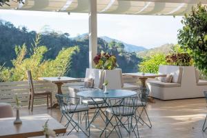 a patio with tables and chairs and a view of mountains at The Retreat Costa Rica - Wellness Resort & Spa in Atenas