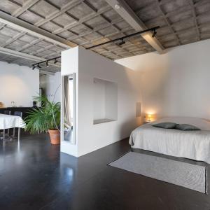 a white bedroom with a bed and a table at Loft van 90 m² met grote binnentuin. in Antwerp