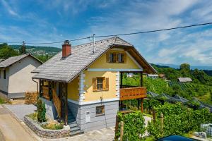 una pequeña casa amarilla con balcón en una colina en Vineyard Cottage Stepan - Happy Rentals, en Črnomelj