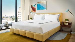 a large white bed in a room with a large window at Thompson Hollywood, by Hyatt in Los Angeles