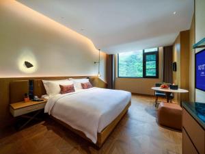 um quarto de hotel com uma cama grande e uma televisão em Novotel Linfen Mount Yun em Xiangning