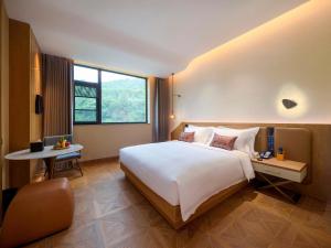 a hotel room with a large bed and a table at Novotel Linfen Mount Yun in Xiangning