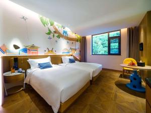 a bedroom with a large white bed with blue pillows at Novotel Linfen Mount Yun in Xiangning