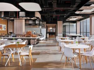 a restaurant with white tables and white chairs at ibis Yogyakarta International Airport Kulon Progo in Yogyakarta