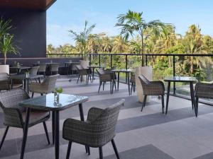 a patio with tables and chairs and palm trees at ibis Yogyakarta International Airport Kulon Progo in Yogyakarta