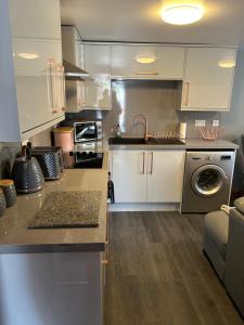 a kitchen with white cabinets and a washing machine at Saint Blue Apartment in Tain