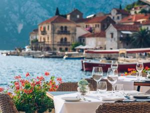 a table with wine glasses and a view of the water at Heritage Grand Perast By Rixos in Perast