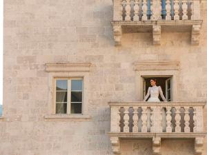Heritage Grand Perast By Rixos في بيراتس: امرأة تقف على شرفة مبنى