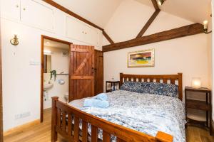 a bedroom with a wooden bed and a bathroom at Dairy Cottage in Roffey