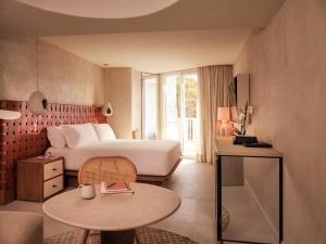 a hotel room with a bed and a table at Mondrian Ibiza in Cala Llonga