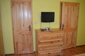 a bedroom with a tv and a wooden dresser with a door at Privat Lubika in Trstené