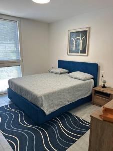 a bedroom with a blue bed and a rug at LabPark Luxury Apartment in Melano