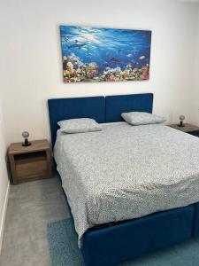 a bedroom with a blue bed and a painting on the wall at LabPark Luxury Apartment in Melano
