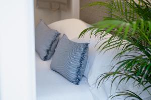 two pillows on a white bed with two plants at Riviera Suites in Civitavecchia