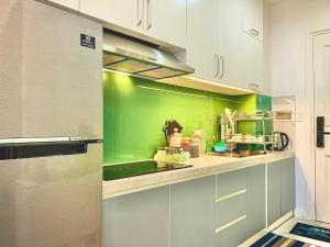 uma cozinha com paredes verdes e armários brancos em Căn Hộ Ocean Vista 1PN em Ấp Ngọc Hải