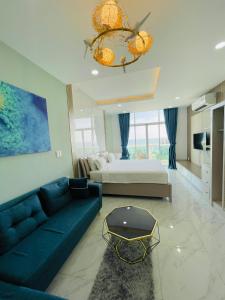 a living room with a blue couch and a bed at Căn Hộ Ocean Vista 1PN in Ấp Ngọc Hải