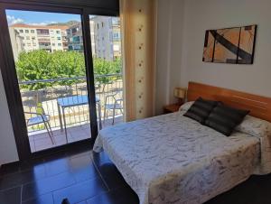 1 dormitorio con cama y vistas a un balcón en Hostal Manel, en Pineda de Mar