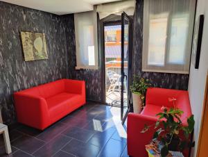 un salon avec deux chaises rouges et une terrasse dans l'établissement Hostal Manel, à Pineda de Mar
