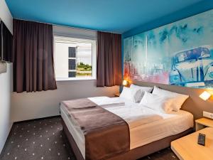 B&B Hotel Wolfsburg-Weyhausen في فولفسبورغ: غرفه فندقيه بسرير ونافذه