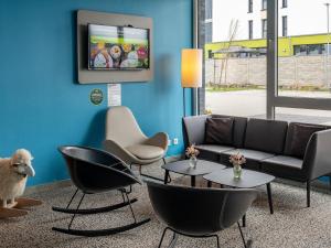 sala de estar con sofá, sillas y TV en B&B Hotel Wolfsburg-Weyhausen en Wolfsburg