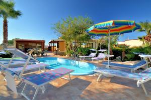 a swimming pool with two chairs and an umbrella at Villa Minoa con piscina in San Vito lo Capo