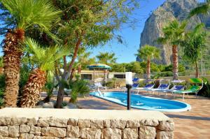 a pool with palm trees and a mountain in the background at Villa Minoa con piscina in San Vito lo Capo