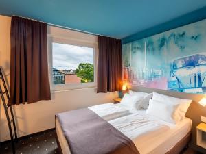 a bedroom with a bed with a large window at B&B Hotel Wolfsburg-Weyhausen in Wolfsburg