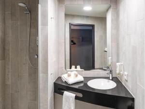 a bathroom with a sink and a mirror at B&B Hotel Wolfsburg-Weyhausen in Wolfsburg