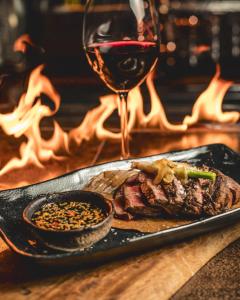 a plate with a steak and a glass of wine at NETFLIX & CHILL in Remetea Mare