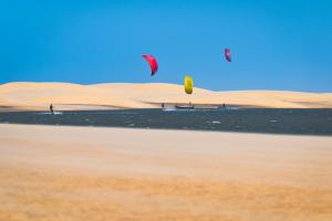 a group of people flying kites in the desert at Paraíso das Canárias in Araioses