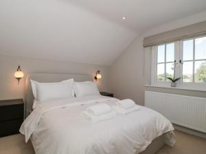 a bedroom with a white bed with two towels on it at The Old Cottage in New Milton