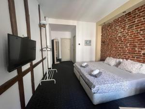 a room with a bed and a tv and a brick wall at Vel House in Plovdiv
