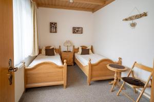 sypialnia z 2 łóżkami, krzesłem i oknem w obiekcie Landhaus Laih w mieście Grafenau