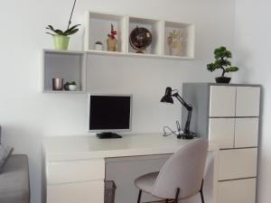 a white desk with a computer monitor and a chair at Well-equipped apartment with free parking in Zagreb