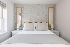 a bedroom with a large white bed with two mirrors at Castle Bank Terrace in Lewes
