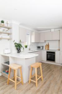 a white kitchen with two wooden stools in it at Little Blue in Chichester