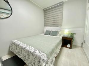 Habitación blanca con cama y espejo en JIBIDA Urban Inn en Seúl