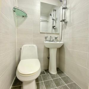 La salle de bains blanche est pourvue de toilettes et d'un lavabo. dans l'établissement JIBIDA Urban Inn, à Séoul