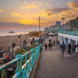 a group of people walking on the beach at sunset at Regency Stables in Brighton & Hove