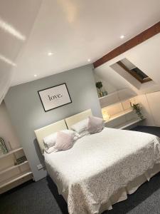 um quarto com uma cama com lençóis brancos e almofadas cor-de-rosa em Solomons Peak Apartment em Buxton