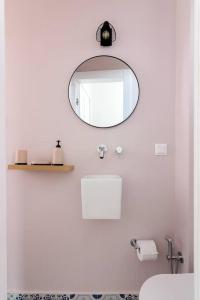 La salle de bains blanche est pourvue d'un miroir et d'un lavabo. dans l'établissement Lavish Mansion House 1928 in Kifisia by UPSTREET, à Athènes