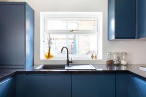 a kitchen with blue cabinets and a sink and a window at The Pride in Worthing