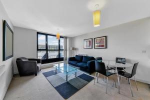 uma sala de estar com um sofá azul e uma mesa de vidro em ComfyCozy Luxury Apartment Canning Town em Londres