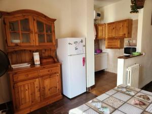 La cuisine est équipée d'un réfrigérateur blanc et de placards en bois. dans l'établissement Casa di Adele, à Anzio
